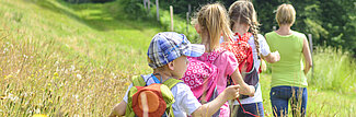 Kinder gehen eine Wanderung über eine Wiese.